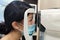 Asian women with surgical mask and optometrist examining eyesight patient in optician office