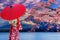 Asian women wear Japanese kimonos. Holding a red umbrella at Mount Fuji and cherry blossoms at Lake Kawaguchiko in Japan