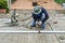 asian worker with machine cutting metal and welded steel to create a roof, local labor construction concept