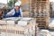 Asian worker stacking bricks in warehouse of building materials on an open-air site