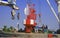 Asian workers group with crane truck are working to transfer red fairway buoys with steel plate into the ship at harbor