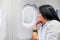 Asian wowan rest hand on chin in airplane cabin near window seat