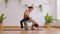 Asian yoga trainer teaches little girl doing back bend yoga in home studio.Bridge pose strengthen back, shoulders, chest for