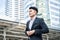 Asian young attractive office businessman worker stand outdoor in city. Happy Employee man in formal wear look around building of