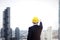 Asian young businessman engineer in suit wearing safety helmet pointing to the sky with skyscraper city, heading to the future