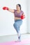 Asian young chubby fat healthy oversized overweight fit female sportswoman in casual sportswear and boxing gloves standing on yoga