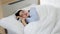 Asian young chubby oversized obese woman wears blue stripe pyjama snore and have deep sleep sweet dream in bed cover by white