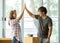 Asian young couple make high five hands after finish packing cardboard box prepare for relocation apartment