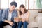 Asian young couple relax looking tablet entertainment on internet together on sofa at home