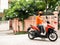 Asian young delivery man send dessert or delicious food in plastic bag arrived at customer home by drive motorcycle while wearing