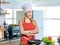 Asian young female chef wears white tall cook hat and apron smiling posing ready to cooking food with pan at counter with bread