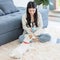 Asian young female owner sitting smiling on carpet floor browsing surfing internet online via laptop computer playing chew ball