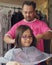 Asian young girl is getting haircut at home from the father. Young teenage girl