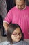 Asian young girl is getting haircut at home from the father. Young teenage girl