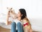 Asian young girl looking and feeding food to adorable Japanese white Shiba Inu and Maltese puppy pet while catching and holding