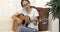 Asian young girl sitting on long sofa chair concentrating focused learning to play guitar at home.