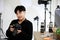 Asian young handsome happy male short black hair photographer hold DSLR camera in hands in photography studio