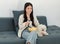 Asian young happy cheerful female owner sitting smiling on cozy sofa couch holding eating popcorn glass bowl snack watching movie