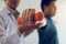 Asian young male physiotherapist helping patient with lifting dumbbells exercises in office