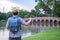 Asian young man age 25-30 year tourists backpacker are watching the beauty of the bridge in the park and tourist attractions with