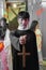 Asian young man dressed as priest holding the cross in hand and  makeup face for blood and wounds at Halloween party