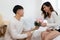 Asian young man kneeling and giving a bouquet of pink flowers to his girlfriend