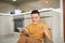 Asian young man work at home, an owner of online business, eating .sausage and looking on tablet