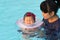 Asian young mother and cute eight month baby in swimming pool.