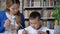 Asian young mother writing with son, women helping kid, sitting behind table, asian kid doing homework, book shelves