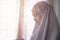 Asian young muslim woman wearing Telekung or white hijab in blurred sitting praying..