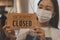 Asian young owner retail,coffee shop woman turning sign board to closed with wearing face mask,protection to pandemic of