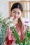 Asian young professional female flower shopkeeper decorator florist standing smiling working decorating flower bunch bouquet in
