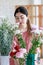 Asian young professional female flower shopkeeper decorator florist standing smiling working decorating flower bunch bouquet in