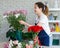 Asian young professional female flower shopkeeper decorator florist wearing jeans apron standing smiling working decorating flower