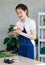 Asian young professional female flower shopkeeper decorator florist wearing jeans apron standing smiling working decorating pink