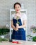 Asian young professional female flower shopkeeper decorator florist wearing jeans apron standing smiling working decorating pink