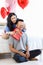 Asian young romantic lover couple female girlfriend giving present wrapped gift box closed boyfriend eyes sitting surprised on bed