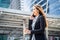 Asian young smart businesswoman talking in telephone in city. The girl holding coffee cup walking outdoor to working office with s