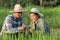 Asian young smart farmer couple using digital tablet monitoring and  managing rice field organic farm. Modern technology smart