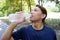 Asian young sportman in navy blue color sportwear Thirsty and resting and drinking water in bottle after exercise and running