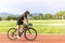 Asian young woman athletes cycling on a race track intently and happily at outdoor sports field in bright day