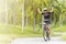 Asian young woman athletes cycling on road and raise hand above head intently at outdoor garden park with sunshine