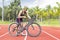 Asian young woman athletes rest stand and handle the bicycle on race track at outdoor sports field on bright day