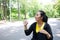 Asian young woman in black and yellow sportwear Thirsty and drinking water in bottle after exercise and running in garden