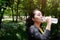 Asian young woman in black and yellow sportwear Thirsty and and drinking water in bottle after exercise and running with natural