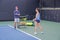 Asian young woman with her trainer practicing outdoor tennis.