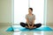 Asian young woman sitting and practices yoga Bound Angle pose on blue mat