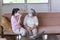 Asian young woman teach elder mother, how to wear face mask from online learn in living room with carefully. family concept