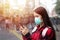 Asian Young woman using smart phone in the city wearing face mask because of air pollution, particulates and for protection flu