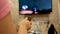 Asian young woman watching TV in the room with remote control in her hand to adjust volume or changing TV channel. Relaxation in l